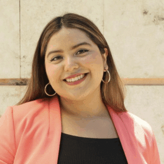 Camila Darina Escalante Martin smiling at the camera against a marble wall.